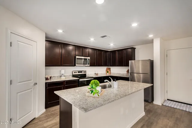 a kitchen with stainless steel appliances granite countertop a sink a stove and a refrigerator