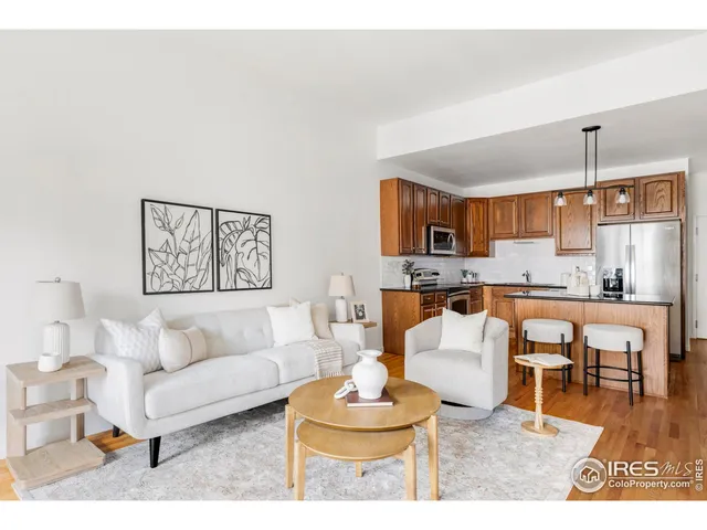 a living room with furniture kitchen view and a wooden floor