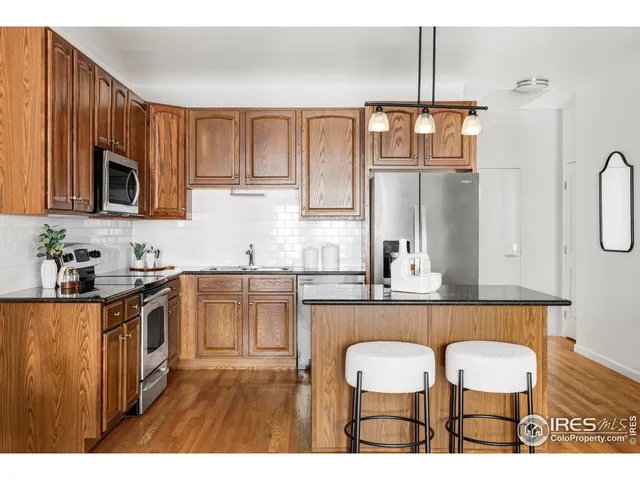 a kitchen with kitchen island granite countertop a sink cabinets and stainless steel appliances