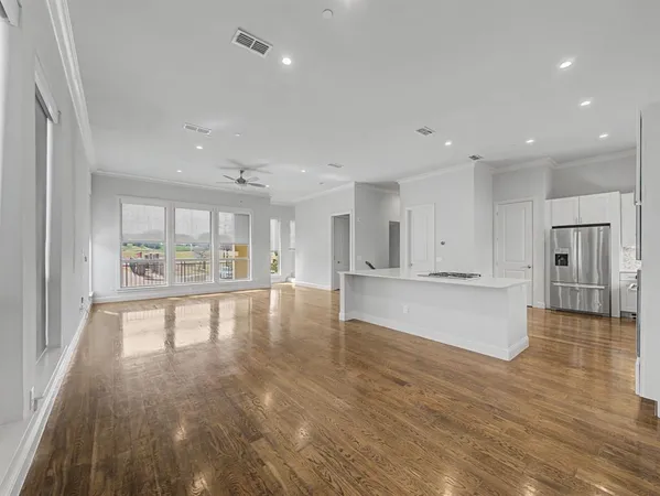 a view of an empty room and kitchen with granite countertop a stove top oven