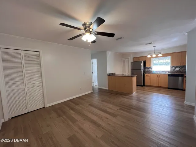 a view of an empty room with wooden floor and a window