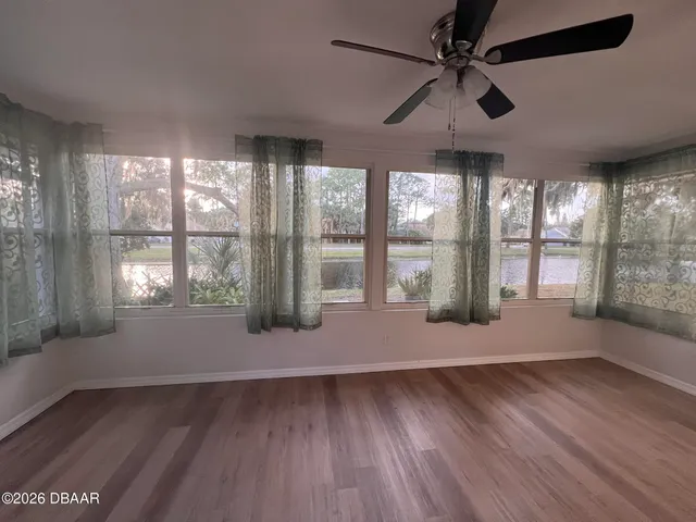 a view of an empty room with window and wooden floor