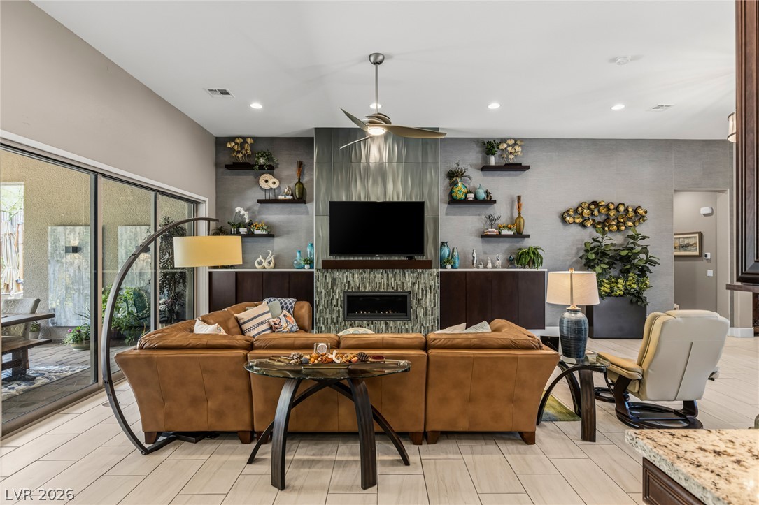 10167 Copper Edge Road Las Vegas, NV 89148 - Photo 8 of 45 A refined living space showcases a built-in fireplace, tile flooring, and a large sliding glass door opening to the outdoors.