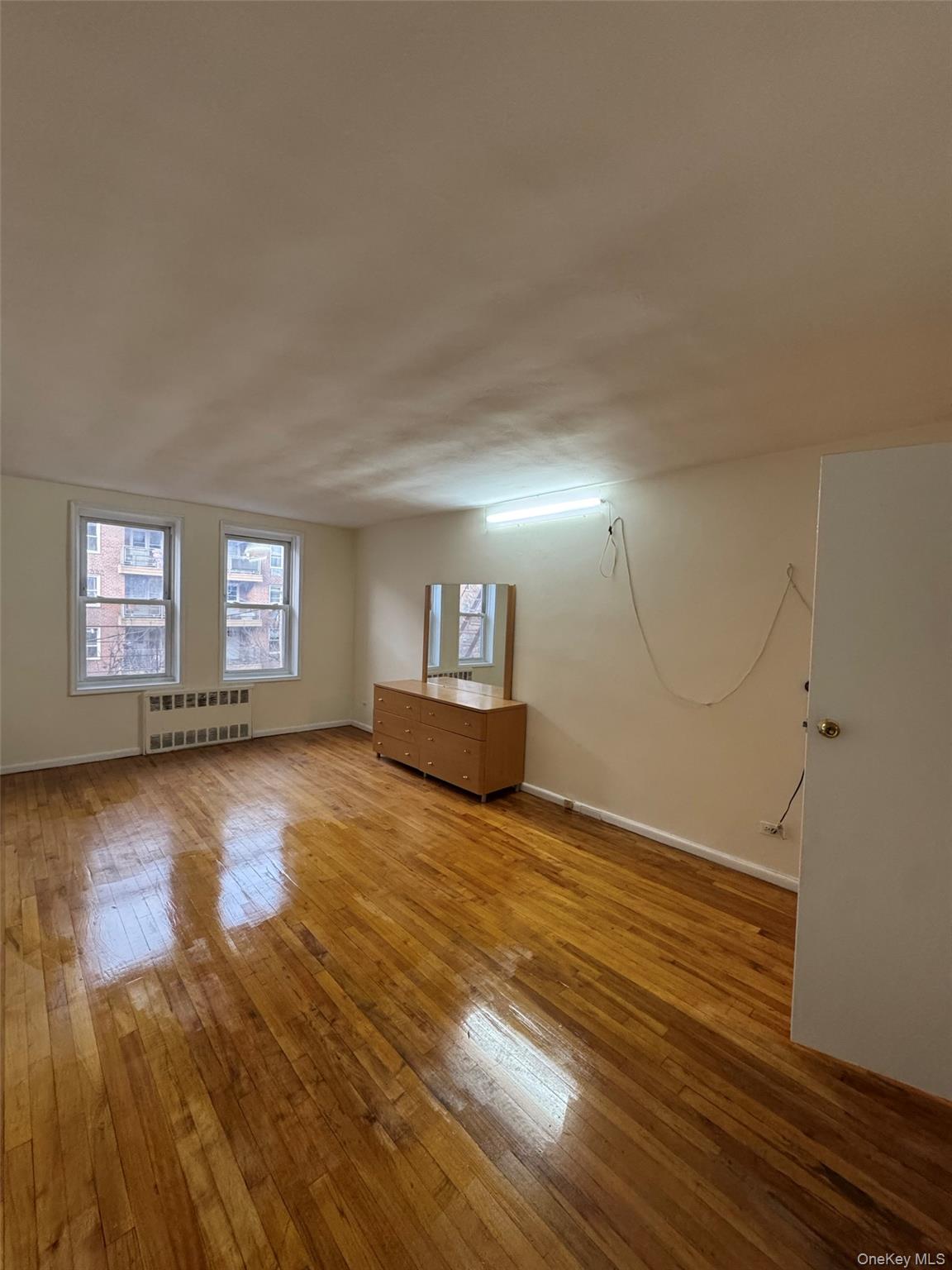 142-20 41st Avenue, Unit 4K Queens, NY 11355 - Photo 4 of 8 Spare room with light wood-style floors and radiator