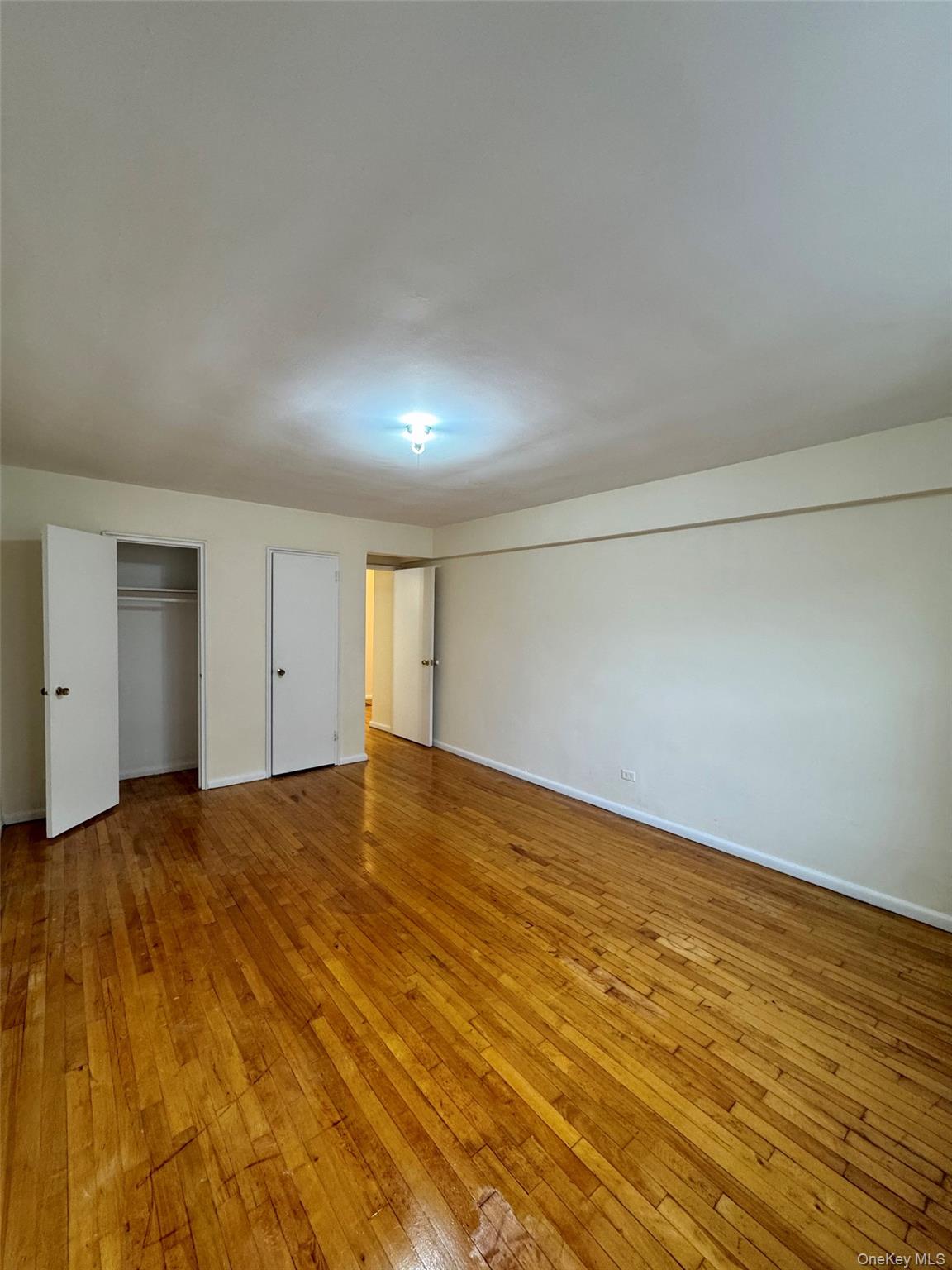 142-20 41st Avenue, Unit 4K Queens, NY 11355 - Photo 6 of 8 Unfurnished bedroom with light wood-type flooring and a closet
