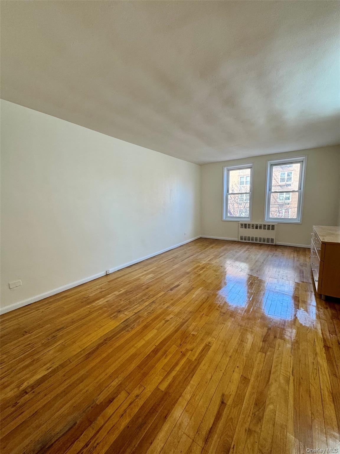 142-20 41st Avenue, Unit 4K Queens, NY 11355 - Photo 7 of 8 Unfurnished room with hardwood / wood-style floors and radiator