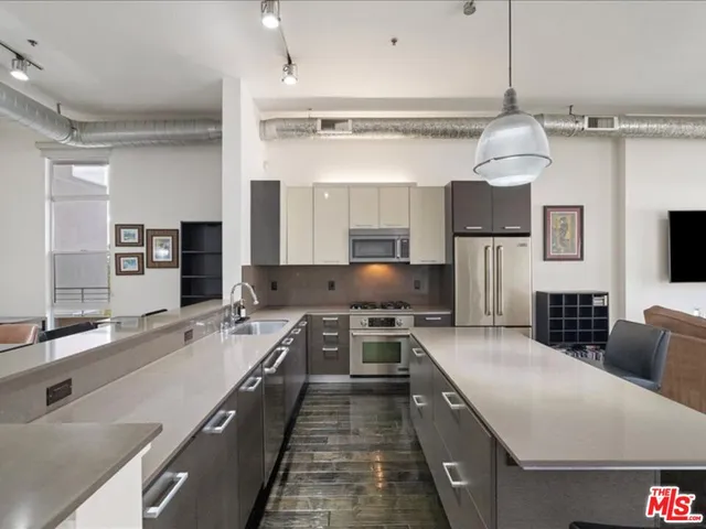 a large kitchen with a large counter top space a sink stainless steel appliances and cabinets