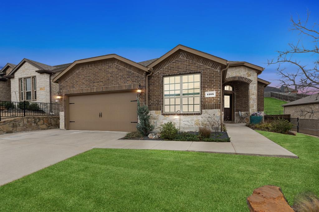 View of front of property with a front lawn, stone siding, fence, concrete driveway, and an attached garage
