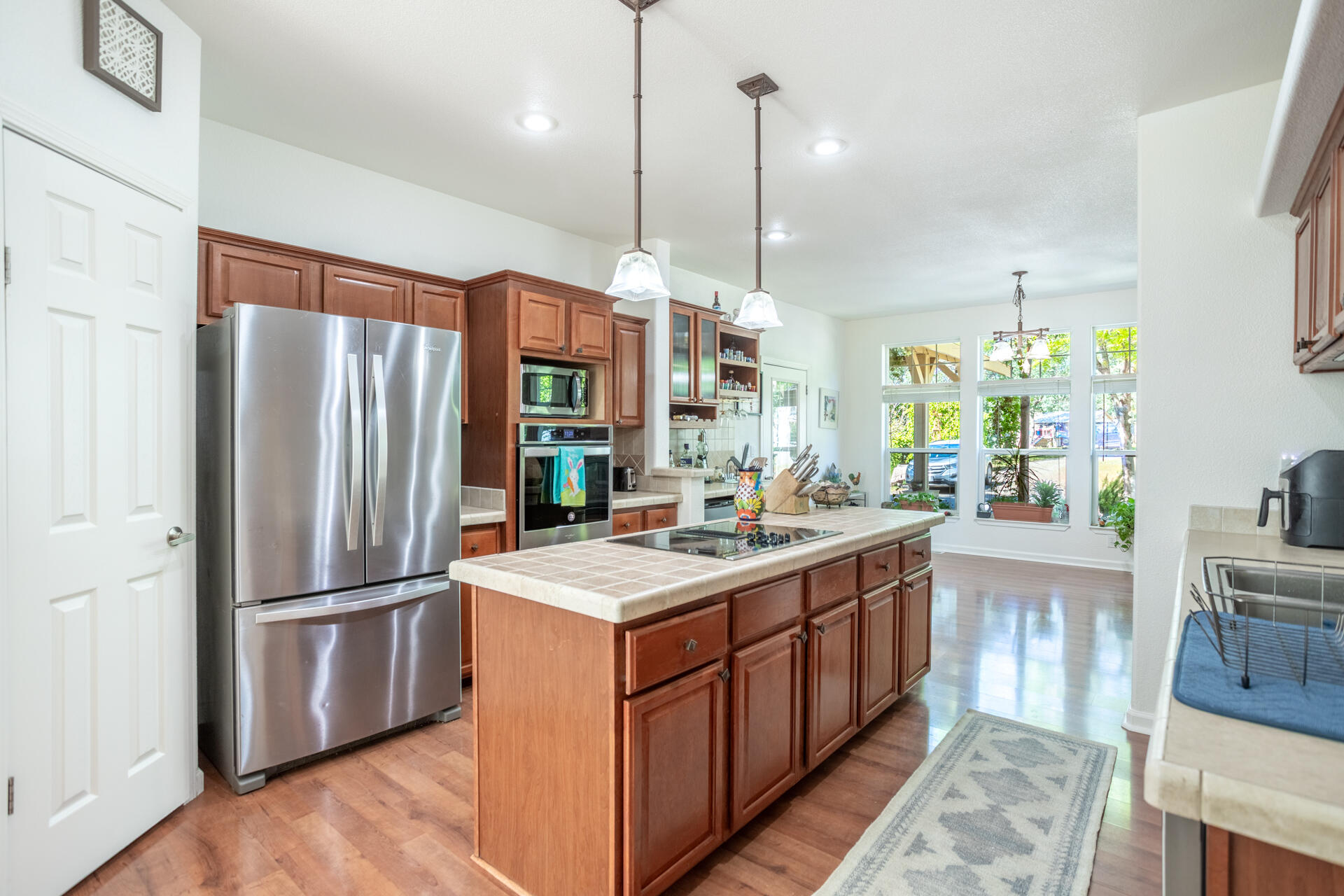 21100 Doe Run Way Red Bluff, CA 96080 - Photo 7 of 93 a kitchen with stainless steel appliances granite countertop a refrigerator a sink dishwasher a oven and a dining table with wooden floor