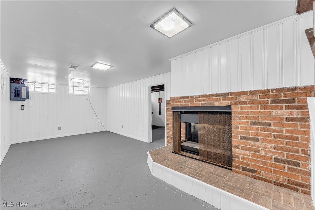 4693 Liberty Road South Euclid, OH 44121 - Photo 26 of 33 Unfurnished living room featuring a fireplace, electric panel, finished concrete floors, and wood walls