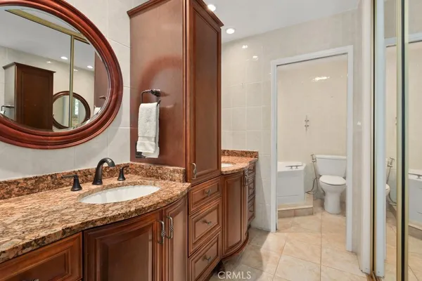 a bathroom with a granite countertop double vanity sink a mirror and a toilet