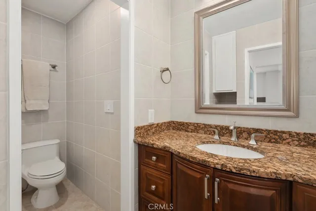 a bathroom with a granite countertop sink a toilet and a mirror