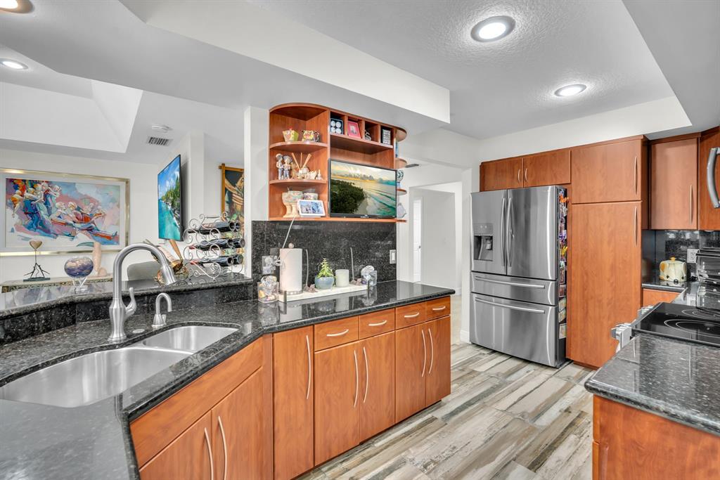 820 Southwest 87th Terrace Plantation, FL 33324 - Photo 26 of 41 a kitchen with stainless steel appliances granite countertop a refrigerator a stove and a sink with wooden floors
