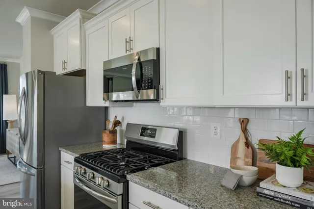 a kitchen with stainless steel appliances granite countertop a stove a refrigerator a sink a counter space and cabinets