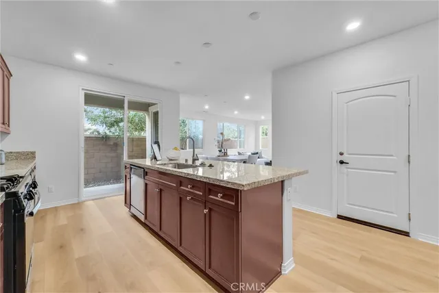 a kitchen with stainless steel appliances granite countertop a refrigerator a stove a sink a dining table and chairs