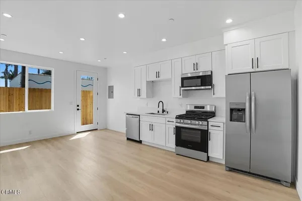 a kitchen with stainless steel appliances white cabinets and wooden floor
