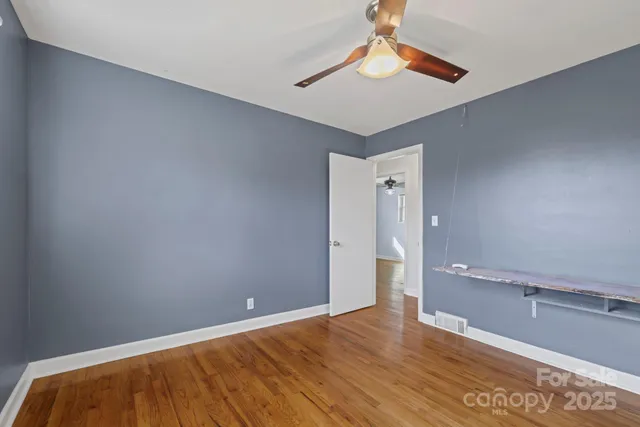 a view of an empty room with window and a ceiling fan