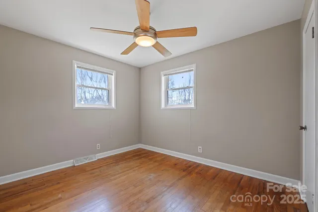 a view of a room with wooden floor and a ceiling fan