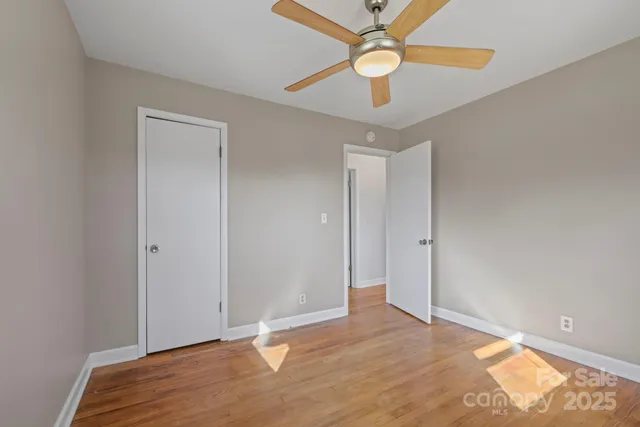 a view of a room with wooden floor and a ceiling fan