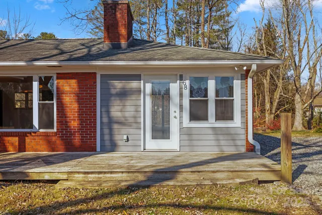 a view of a house with small yard plants and large tree