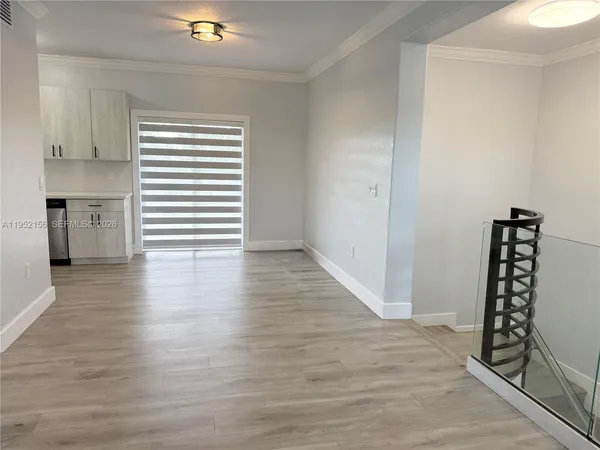 a view of an empty room with window and wooden floor