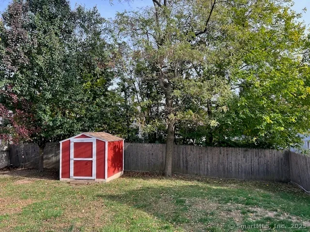 a view of a backyard with large trees and wooden fence
