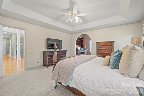 a bedroom with a large bed a flat tv screen and a chandelier