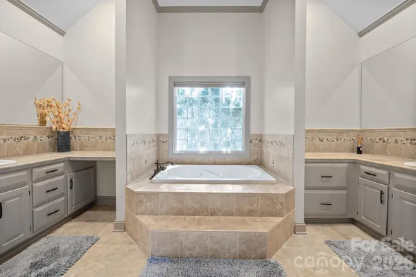 a spacious bathroom with a granite countertop sink a mirror and a bathtub