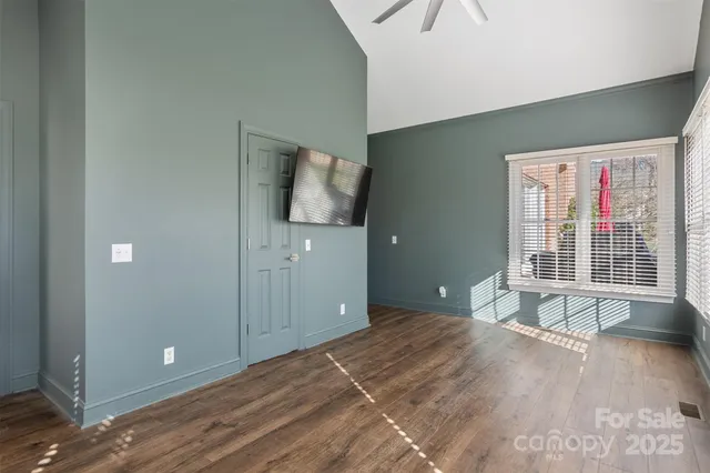 a view of empty room with wooden floor and fan