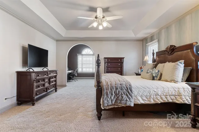 a bedroom with a bed and a flat tv screen on dresser