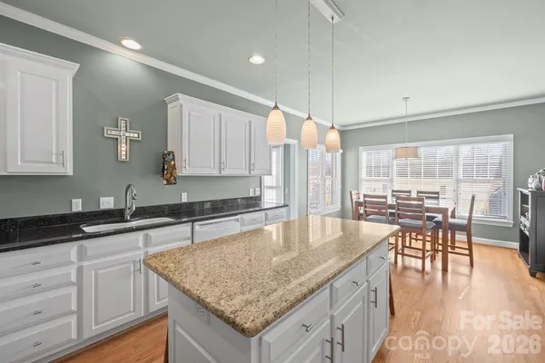 a kitchen with granite countertop kitchen island a table and chairs in it