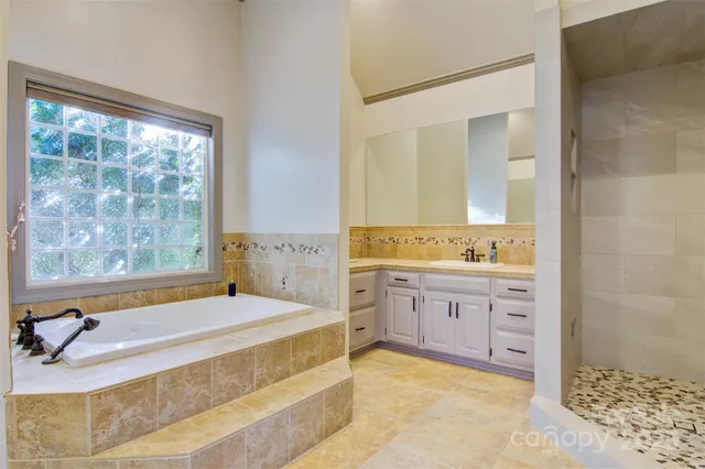 a spacious bathroom with a tub sink and mirror