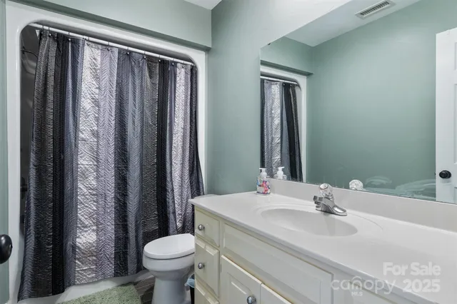 a bathroom with a granite countertop toilet sink and mirror
