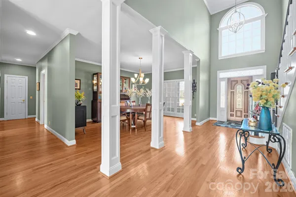 a view of a hallway with wooden floor table and chairs