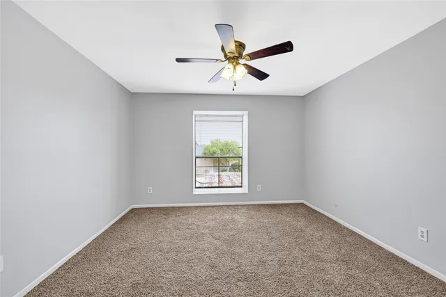 an empty room with a window and a ceiling fan