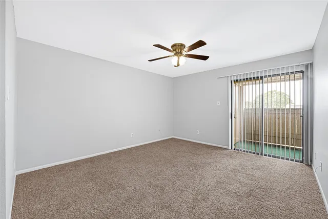 an empty room with a window and a ceiling fan
