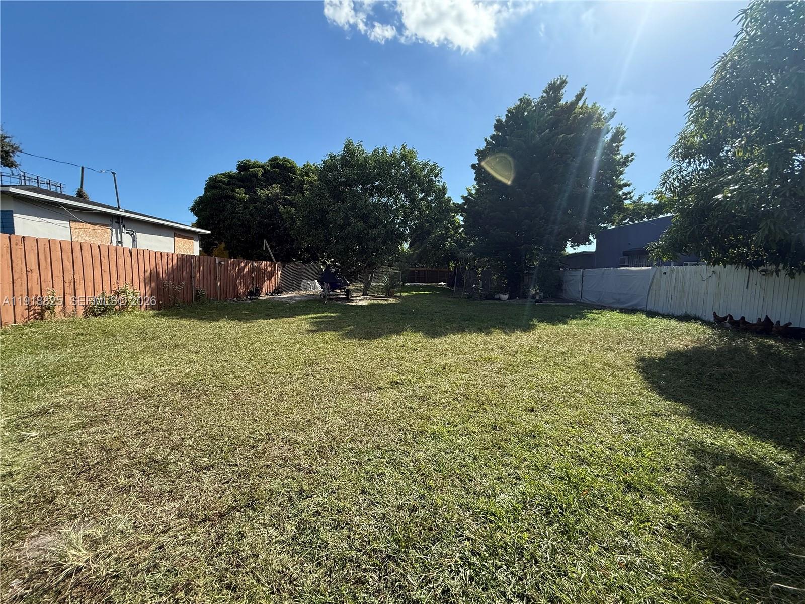 1736 Northwest 42nd Street Miami, FL 33142 - Photo 2 of 4 a view of a backyard with plants and large trees