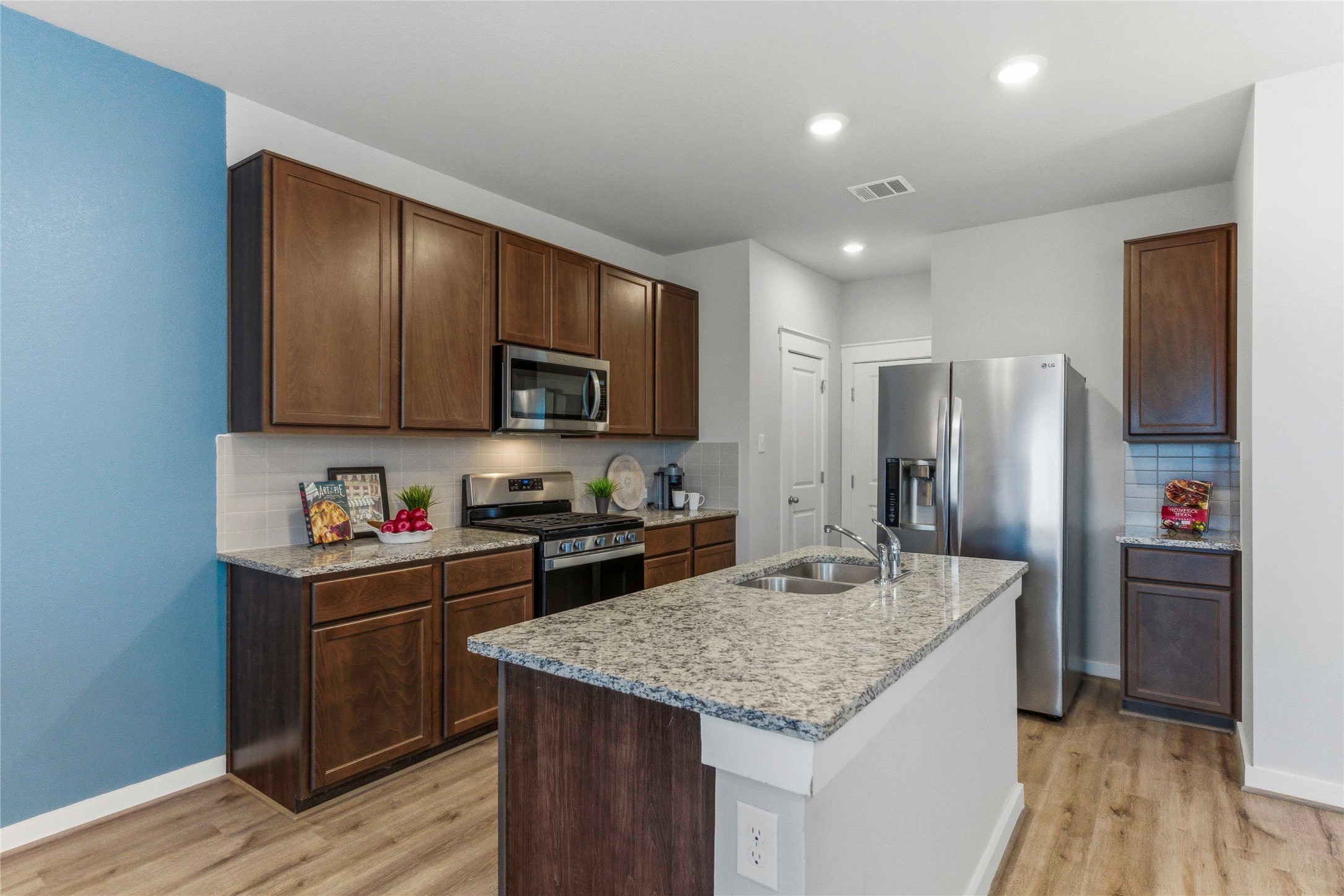 17203 Leafroller Drive, Unit B Pflugerville, TX 78660 - Photo 6 of 20 a kitchen with stainless steel appliances granite countertop a refrigerator a sink dishwasher a stove and a microwave oven on granite countertops with wooden floor