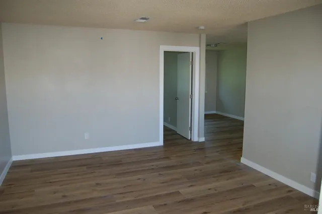 a view of an empty room with wooden floor and closet