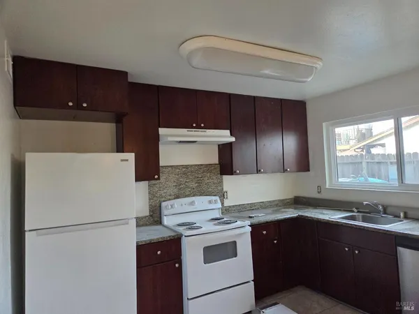 a white refrigerator freezer sitting inside of a kitchen with stainless steel appliances granite countertop cabinets and a refrigerator