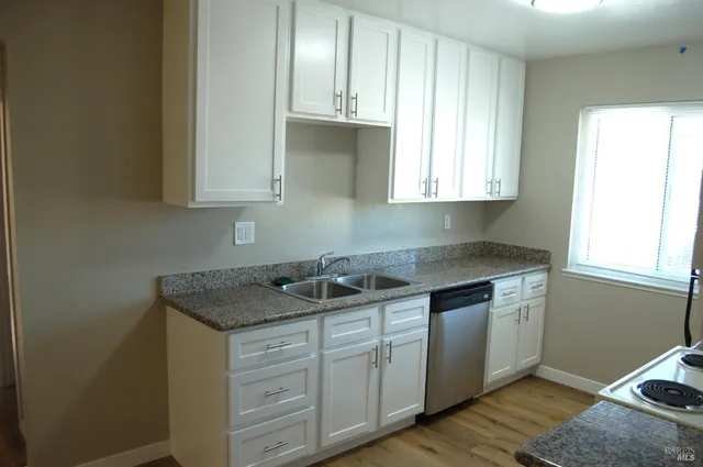a kitchen with cabinets appliances a sink and a window