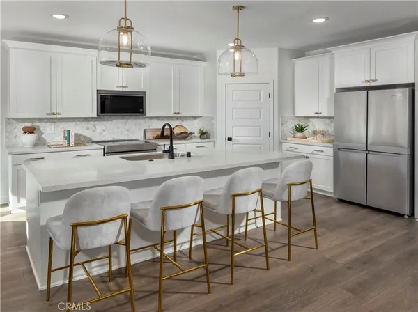 a kitchen with stainless steel appliances kitchen island granite countertop a table chairs microwave and sink