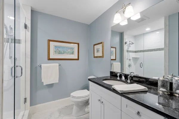 a bathroom with a granite countertop sink a toilet and a mirror