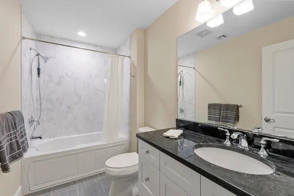 a bathroom with a granite countertop sink toilet mirror and shower
