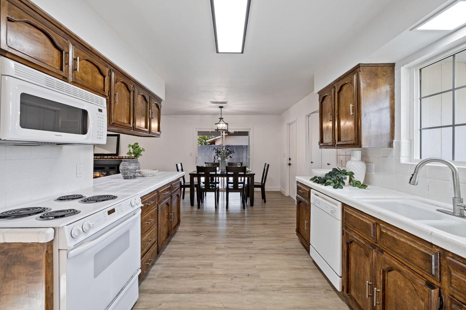 17153 Rodeo Drive Madera, CA 93638 - Photo 12 of 22 a kitchen with stainless steel appliances a stove top oven a sink a dining table and chairs