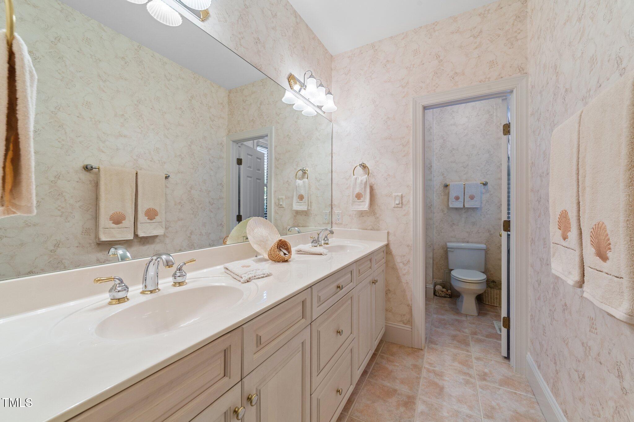 12504 Bayleaf Church Road Raleigh, NC 27614 - Photo 33 of 73 a spacious bathroom with a double vanity sink toilet and a mirror