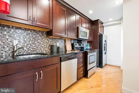 a kitchen with stainless steel appliances granite countertop a refrigerator a sink and wooden cabinets