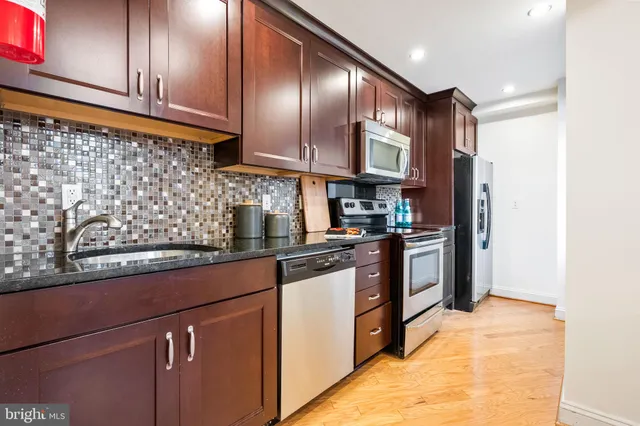 a kitchen with stainless steel appliances granite countertop a refrigerator a sink and wooden cabinets