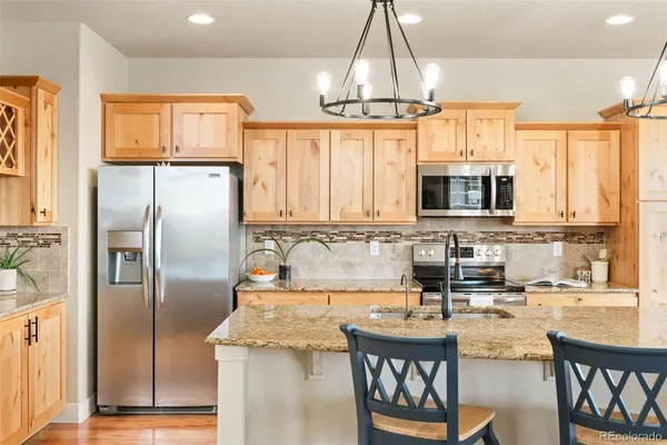 a kitchen with stainless steel appliances granite countertop a sink a stove and a refrigerator