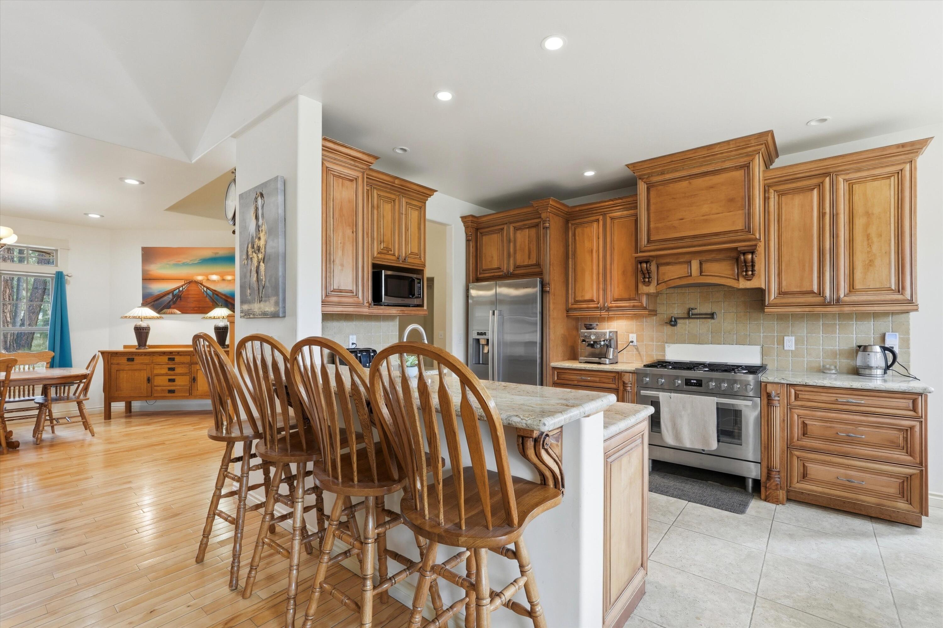 17179 Island Loop Way Bend, OR 97707 - Photo 16 of 52 a kitchen with stainless steel appliances kitchen island granite countertop a stove top oven a sink a dining table and chairs